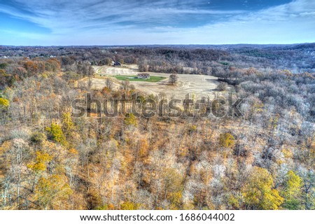 Aerial View of Woods in Fall Colors with a Farmhouse 