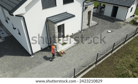 Aerial view of a worker working with a vibrating plate machine in front of a house