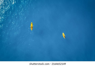 Aerial view of yellow kayaks in blue sea at sunset in summer. Man and woman on floating canoe in clear azure water. Lefkada island, Greece. Tropical landscape. Sup boards. Active travel. Top view - Powered by Shutterstock