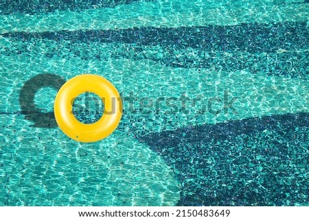 Aerial view of yellow ring float in a  blue swimming pool under bright sunny day