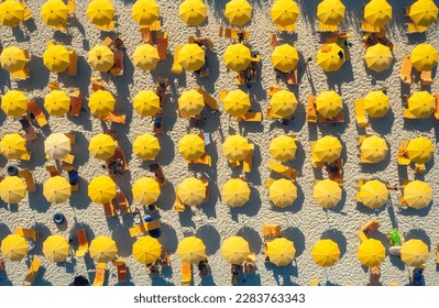 Aerial view of yellow umbrellas on sandy beach at sunset in summer in Sardinia, Italy. Tropical colorful landscape. Travel and vacation background. Top down view from drone. Tropical pattern. Concept - Powered by Shutterstock