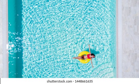 Aerial View Of Young Brunette Woman Swimming On The Inflatable Big Yellow Ring In Pool