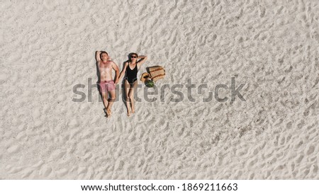 Aerial view of a young couple lying on the white beach sand. man and woman in swimwear spend time together and travel through the desert