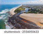 Aerial views of muddy waters from Cudgen Creek flowing in to the sea at Kingscliff headland seawall along the east coast of New South Wales, Australia