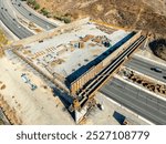 Aerial Wallis Annenberg Wildlife Crossing at Liberty Canyon, bridge crossing under construction over the 101 freeway, highway. Santa Monica mountains in background