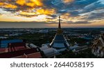An aerial Wat Ketmadi Sriwararam perspective showcasing a stunning Thai temple complex with intricate golden spires, surrounded by urban and rural landscapes under a cloudy blue sky.
