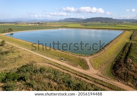 Aerial of a water containment pond pumping from a nearby large dam for farm irrigation supply