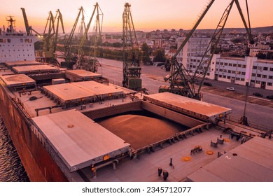 Aerial of wheat loading to bulker ship cargo hold at sea grain elevator in sea port at sunset. Black Sea Grain Initiative and grain deal