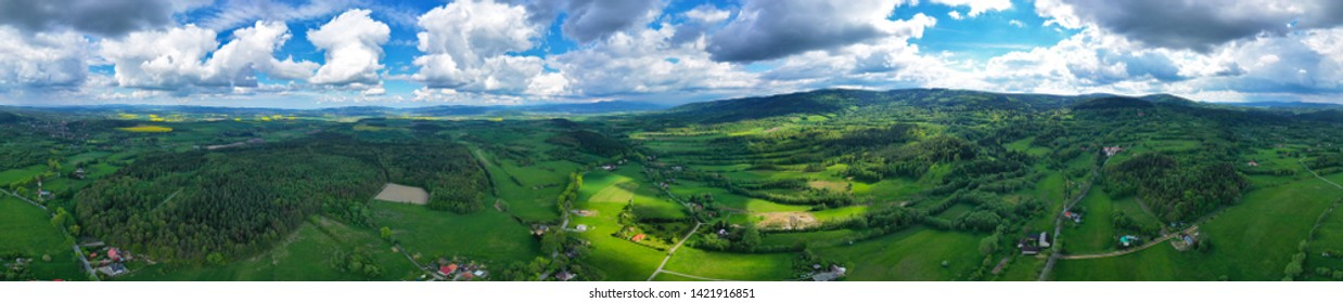 Aerial wide panoramic view on sudety mountains with touristic city in the valley surrounded by meadows, forest and rapeseed fields. - Shutterstock ID 1421916851