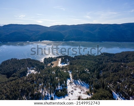 Aerial winter view of Dospat Reservoir covered with ice, Smolyan Region, Bulgaria