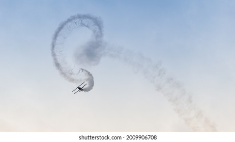 An aerobatic display of a vintage biplane with smoke