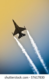 Aerobatic Military Jet In A Gradient Sky Leaving A Smoke Trail
