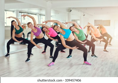 Aerobics class at a gym with a group of attractive fit young women in colorful sportswear working out in together, in a wellness, health and fitness concept