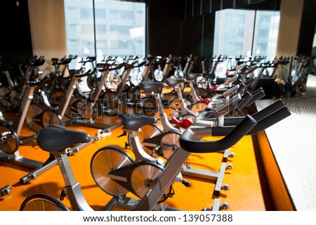 Aerobics spinning exercise bikes gym room with many in a row