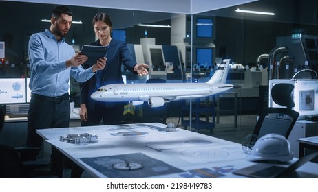 Aeronautics Factory Office Meeting Room: Chief Engineer Holds Tablet Computer, Showing Augmented Reality Airplane to a Female Project Manager, They Test Aerodynamics. Modern Industry 4.0 Research. - Shutterstock ID 2198449783