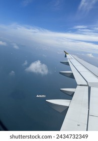 Aeroplane flight..wing plane view from window insight. Blue sky and sea awesome ambience. Ship looks small from sky just like white line.