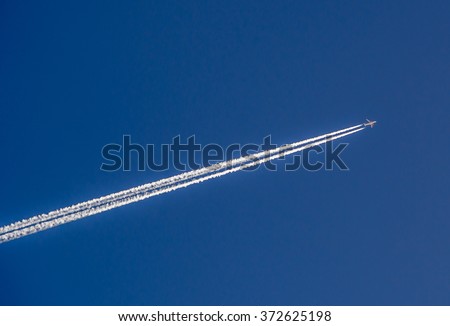Aeroplane flying through clear blue sky with vapour trails