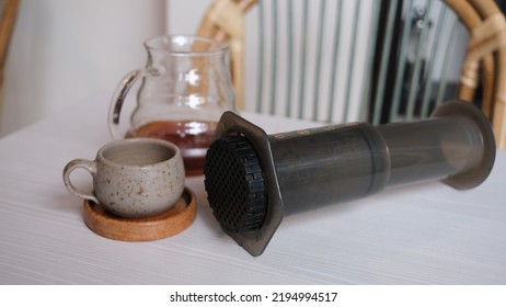 Aeropress Cofee Maker And Coffee Server With A Small Cup On A White Table.