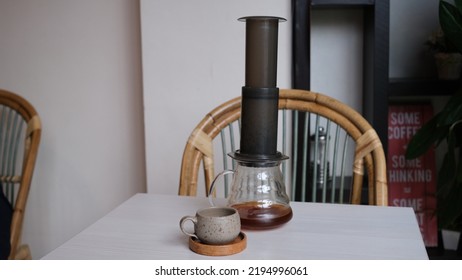 Aeropress Cofee Maker And Coffee Server With A Small Cup On A White Table.