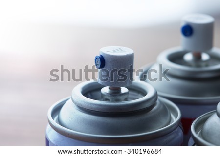 Aerosol spray cans nozzle close up. Several spray cans with light in background. Shallow depth of field.