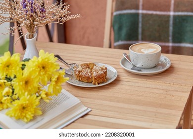 Aesthetic autumn lunch - coffee time for yourself book and dessert. Cutting doughnut with cappuccino among chrysanthemum. Atmospheric lunch, guilty pleasure - Shutterstock ID 2208320001