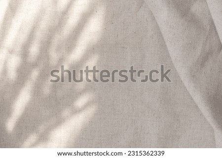 Aesthetic boho wedding textile background, draped neutral beige linen fabric texture with an absrtact floral sunlight shadows