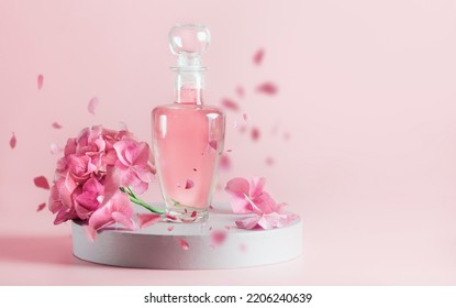 Aesthetic cosmetic product in glass bottle with pink liquid with hydrangea flowers and falling petals on podium. Front view.  - Shutterstock ID 2206240639