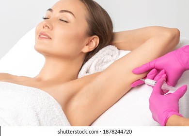 Aesthetic cosmetologist makes lipolytic injections to burn fat on the arm and body of a woman. Female aesthetic cosmetology in a beauty salon.Cosmetology concept.