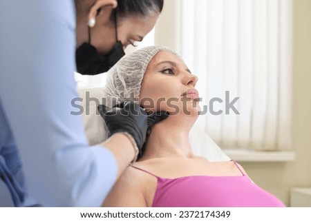 aesthetic doctor is seen in act of injecting filler into jowls of patient lying on chair, part of sophisticated facial contouring procedure. cosmetology clinic offers advanced anti-aging solutions