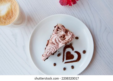 Aesthetic fruit chocolate cake and a glass with a double bottom of latte on wooden table outdoor. Pink flowers decorations in the cafe terrace. Atmospheric breakfast. Top view. - Shutterstock ID 2208320017