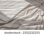 Aesthetic lifestyle bohemian background, business branding template. Crumpled soft neutral beige linen bedsheet fabric texture with folds and natural lifestyle sunlight shadows.