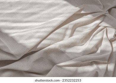 Aesthetic lifestyle bohemian background, business branding template. Crumpled soft neutral beige linen bedsheet fabric texture with folds and natural lifestyle sunlight shadows.