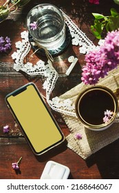 Aesthetic Lifestyle Flat Lay, Wireless Headphones, Mockup Screen Of Phone, Lilac Flowers Decorations, Cup Of Coffee And Glass Of Water.Listening Music Or Audiobook, Surfing Phone Lifestyle