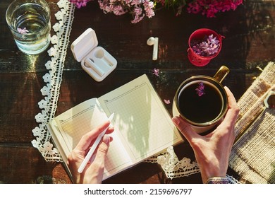 Aesthetic Lifestyle - Wireless Headphones, Lilac Flowers Decorations And Cup Of Coffee. Listening Music Or Audiobook,taking Webinar Or Online Chat Speaking By Phone In The Garden. Notepad Mockup