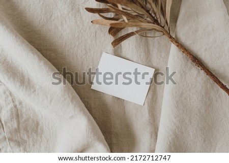 Aesthetic luxury bohemian branding or invitation card template. Blank paper, invitation card sheet with empty mock up copy space, dried protea flower on neutral beige crumpled linen cloth