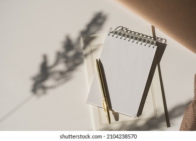 Aesthetic luxury workspace template. Spiral flip notebook with copy space in plant sunlight shadow on white background. Schedule, notes concept for blog, social media, web