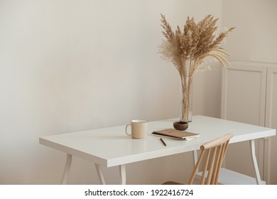 Aesthetic minimal office workspace interior design. Mug, notebook, pampas grass floral bouquet on white table against white wall. Girl, woman boss work at home business concept. - Shutterstock ID 1922416724