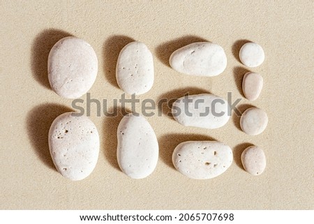 Aesthetic minimal pattern with set of pebble stones on fine sand background. Square composition from natural stone neutral beige color.  Summer concept of harmony, balance, relax. Top view, flat lay.
