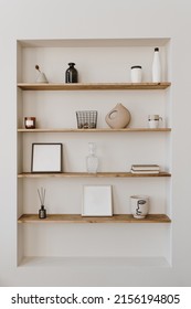 Aesthetic Modern Minimalist Scandinavian Home Interior Decorations. Elegant Bohemian Living Room With White Wall, Shelves With Candle, Picture Frame, Storage Box, Bottle, Vase, Fragrance