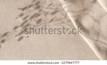 Aesthetic natural minimalistic background, elegant sunlight floral shadows on a neutral beige linen texture pleated tablecloth, background with copy space