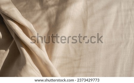 Aesthetic natural textile background with abstract sunlight shadow, neutral beige linen draped fabric, copy space