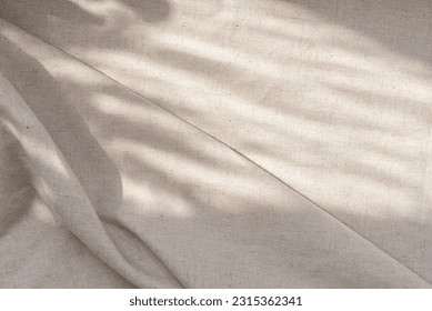 Aesthetic neutral beige linen texture background with a soft abstract sunlight shadows and folds