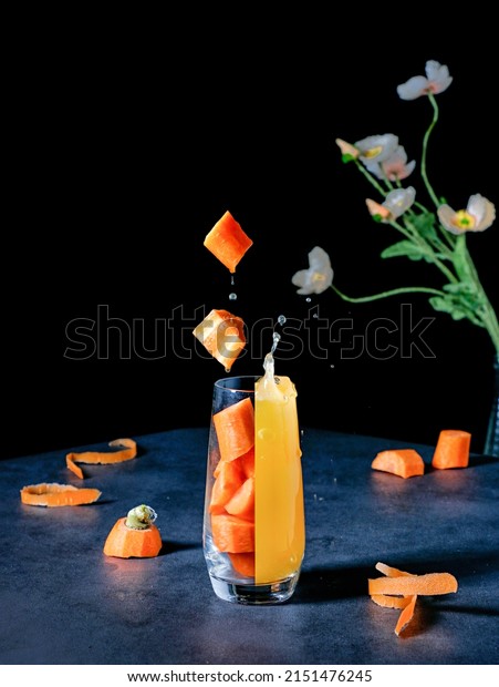 An aesthetic vibrant shot of a glass\
divided into a fresh juice and carrot\
pieces