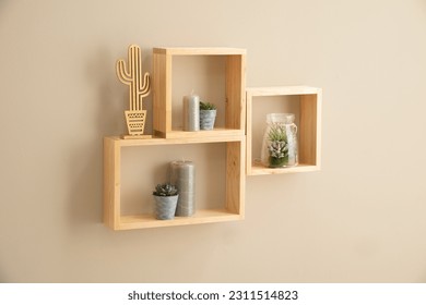 An aesthetically pleasing still-life featuring a selection of small wooden cube shelves, a cactus plant and a glass vase