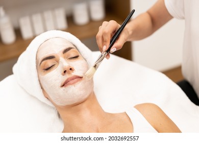 Aesthetics applying a mask to the face of a Middle-aged woman in modern wellness center. - Shutterstock ID 2032692557