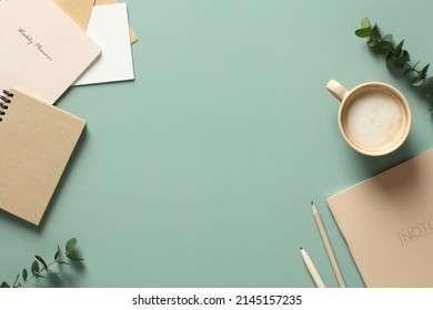 Aesthetics minimal workspace with paper notebooks, coffee cup, eucalyptus leaves on green table. Flat lay, top view - Shutterstock ID 2145157235