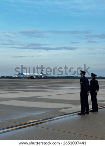 AF One on the tarmac, with two enlisted Airmen in foreground