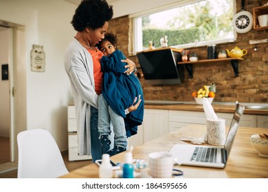 Affectionate African American Mother Carrying Her Ill Daughter In Her Arms At Home.