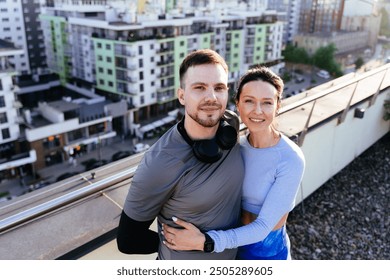 Affectionate Caucasian couple take a selfie portrait through smart phone at on rooftop terrace with city view on background. Sport and fitness healthy lifestyle. - Powered by Shutterstock