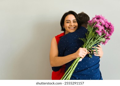 Affectionate couple embracing and holding a bouquet of pink flowers, enjoying a romantic valentine's day celebration with love and tenderness - Powered by Shutterstock